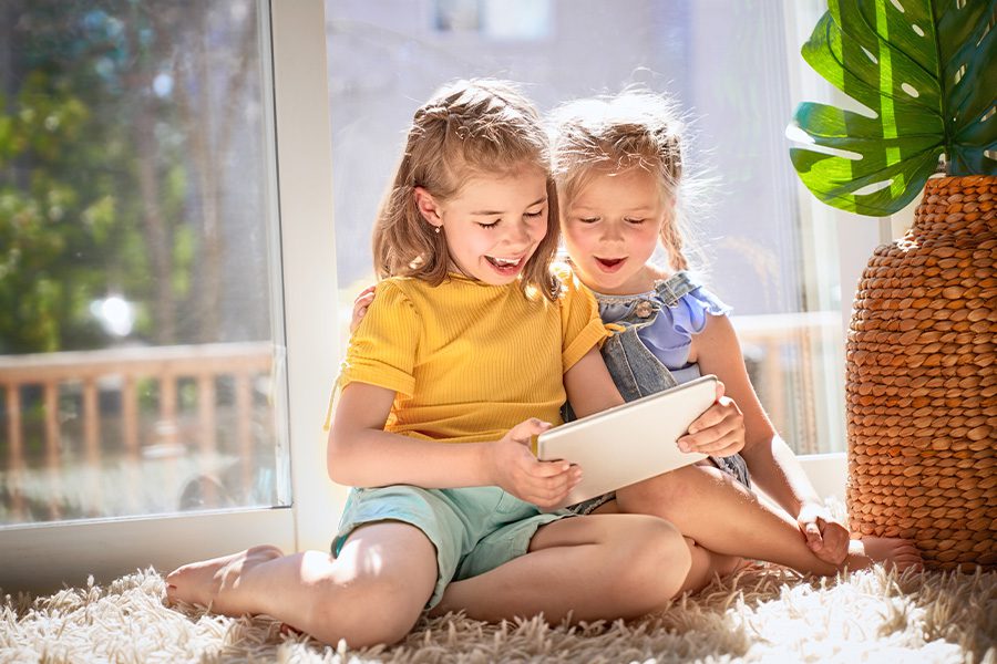 Client Center - Young Children Playing with Tablet and Sitting on the Floor