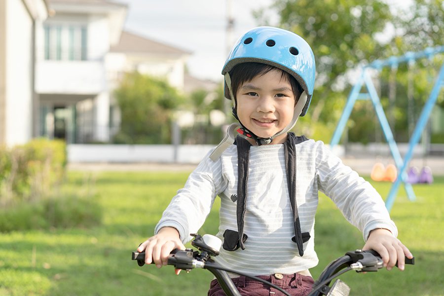 Employee Benefits - Smiling Boy in Safety Helmet Riding His Bike in the Park