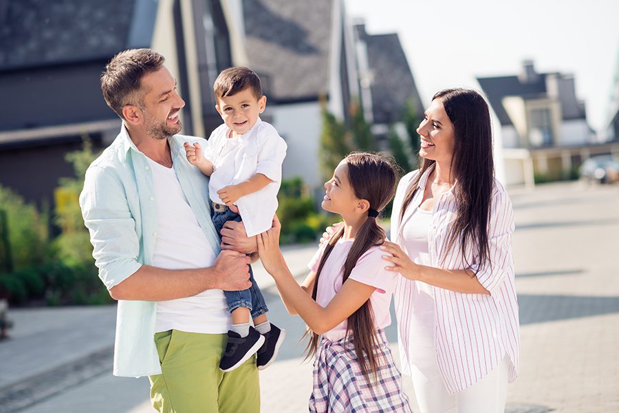 Personal Insurance - Happy Family Looking at Youngest Child Walking Outside Near Their Home